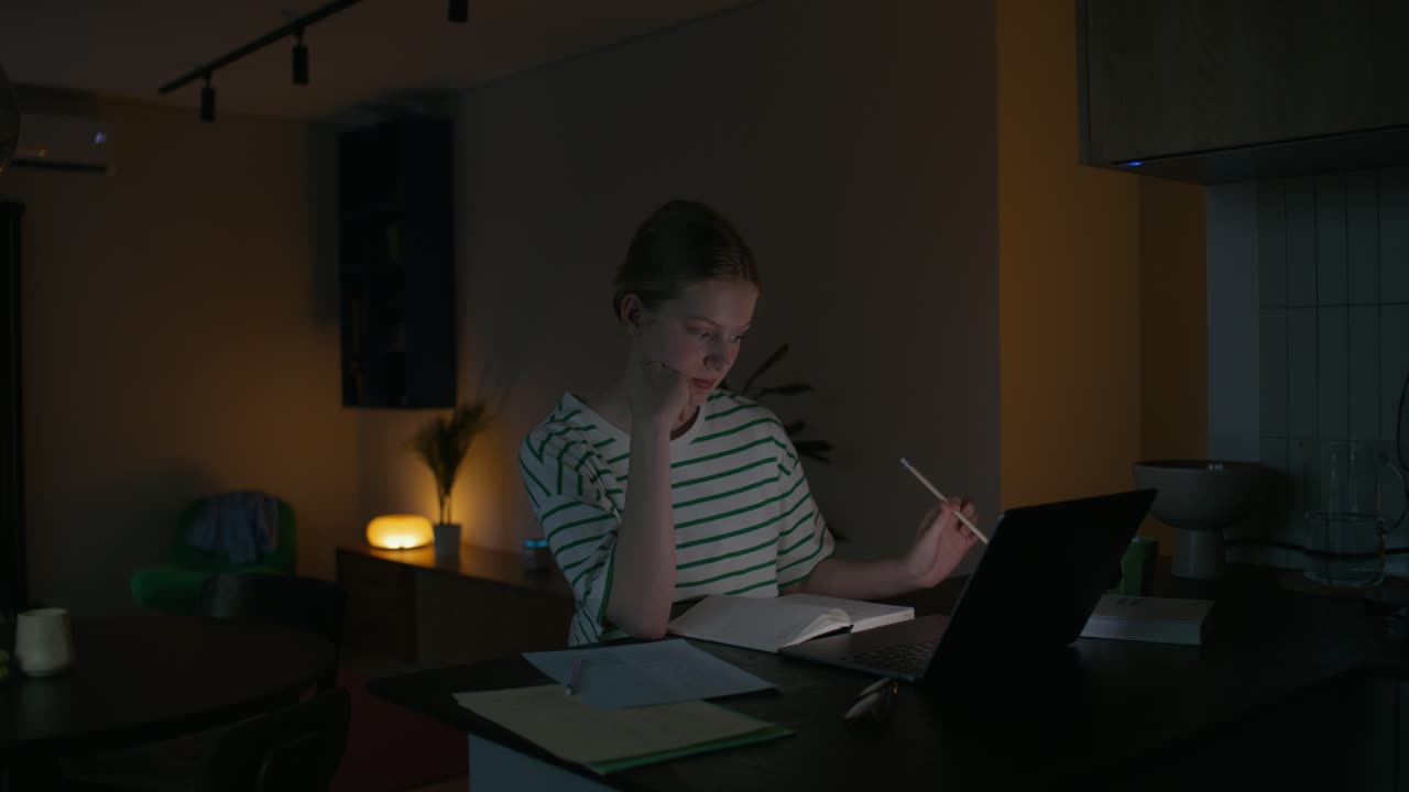 una adolescente estudiando hasta tarde en la noche.