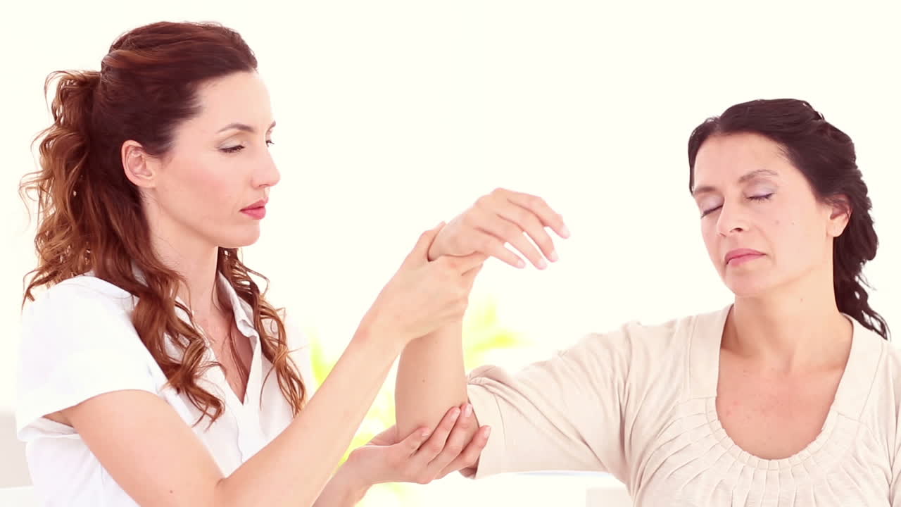 치료사는 환자의 팔을 들고 있습니다.