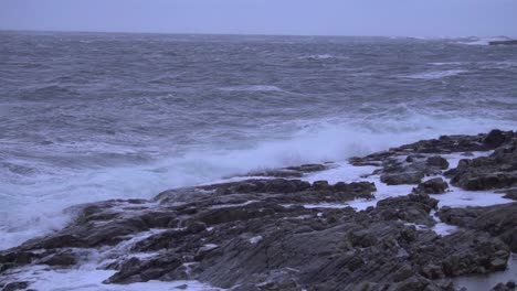 slow motion shot of waves crashing into rocky shore, ocean view.