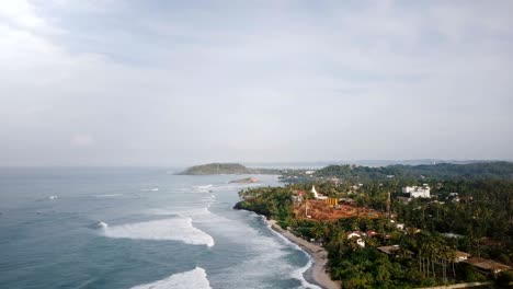 drone rising above beautiful foaming sea waves, coastline and building construction site to reveal amazing lagoon