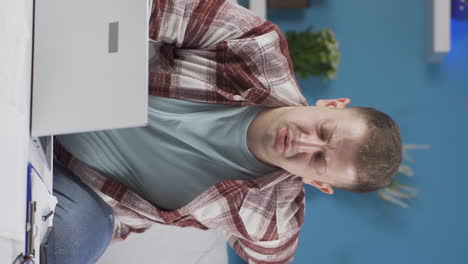 Vertical video of Home office worker man has lower back pain.