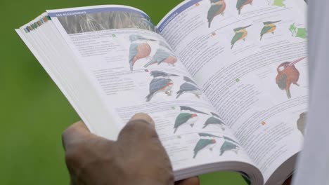 man looking at book of birds and wildlife