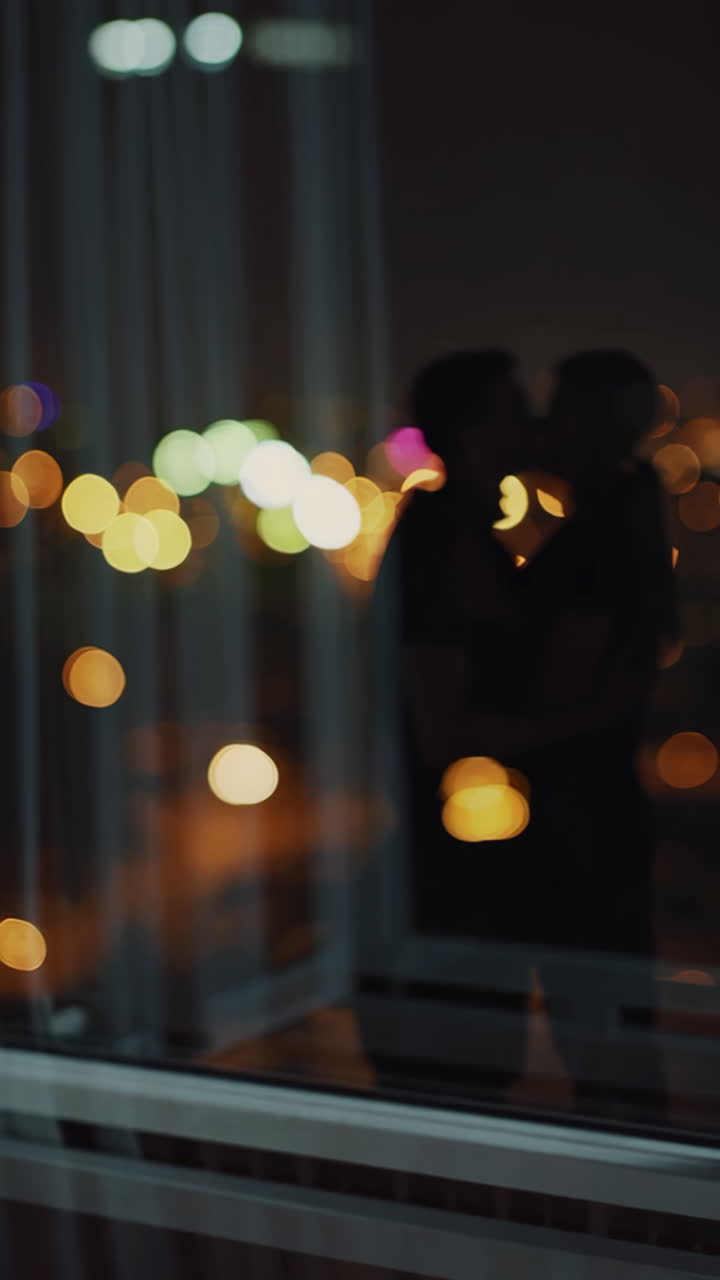 Romantic Night View: A Couple Embracing by the Window with City Lights