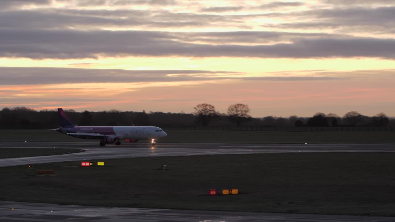 Wizzair plane on the runway at sunrise.