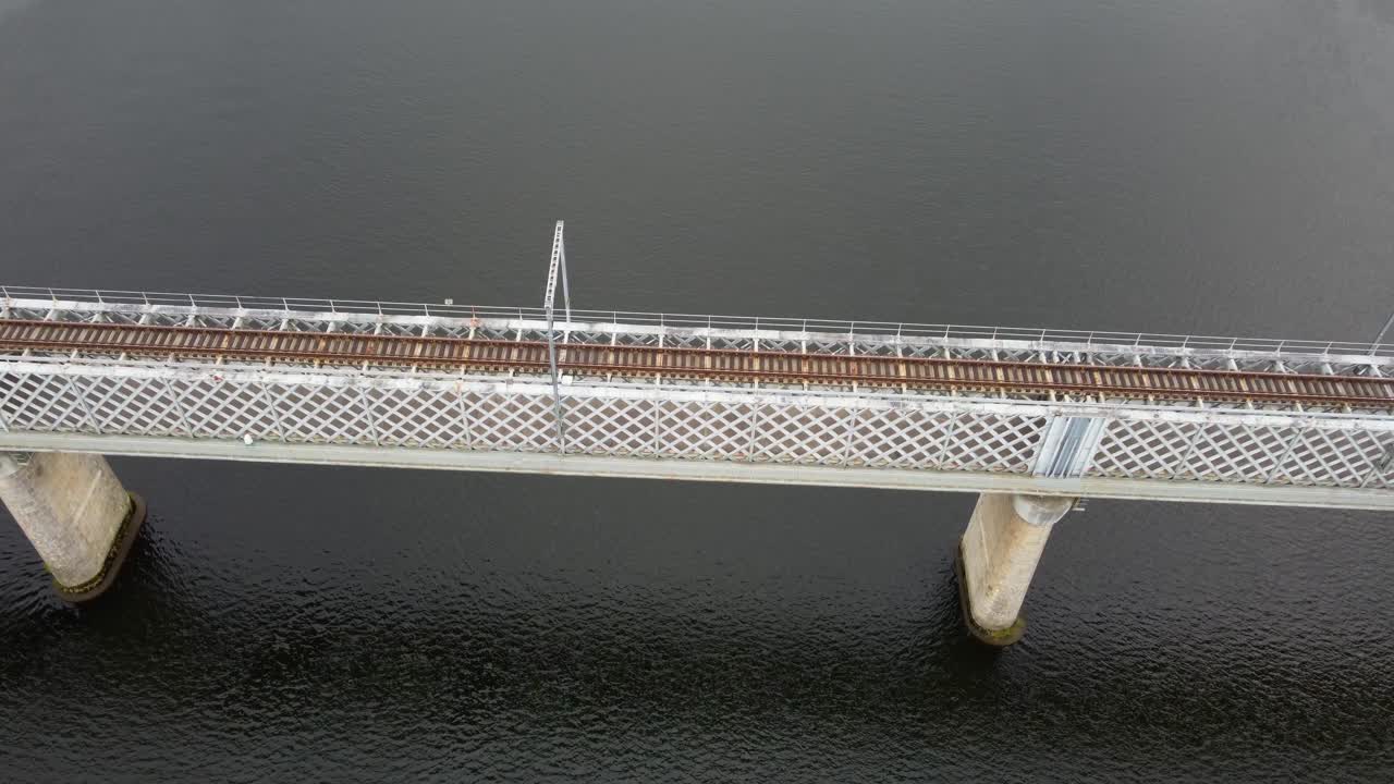 4K drone close-up shot approaching a metal railway bridge over the dark waters of the Minho River, detailing the train tracks and supporting concrete piers, Tui, Spain