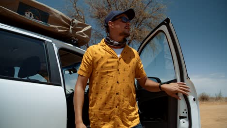 hand held tracking shot of a caucasian male tourist in africa as he gets out of his off-road vehicle and starts to inspect the camping site he has chosen.