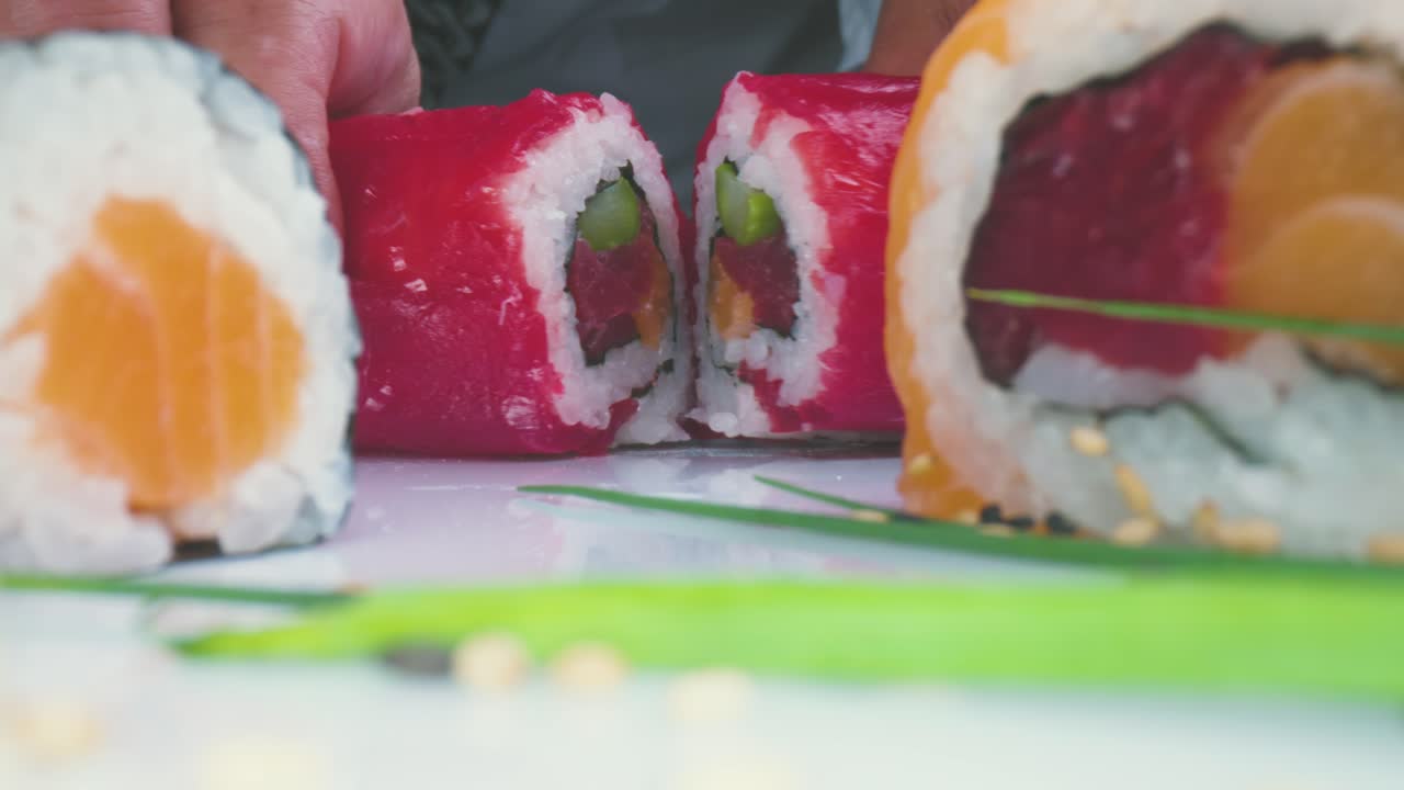 cocinero de cultivos dividiendo rollos de sushi