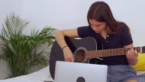 young woman with laptop playing guitar