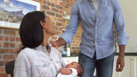 Madre-Trabajando-En-Una-Computadora-Portátil-Sostiene-A-Su-Hijo-Recién-Nacido-Con-Su-Padre