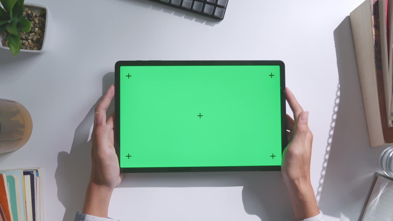 초록색 화면을 모방한 노트북 컴퓨터의 상단에서 아래로 볼 때, 펜, 안경, 그리고 물 한 잔을 가진 노트북 에 나무 사무실 책상 위에 크로마키 디스플레이가 있습니다.