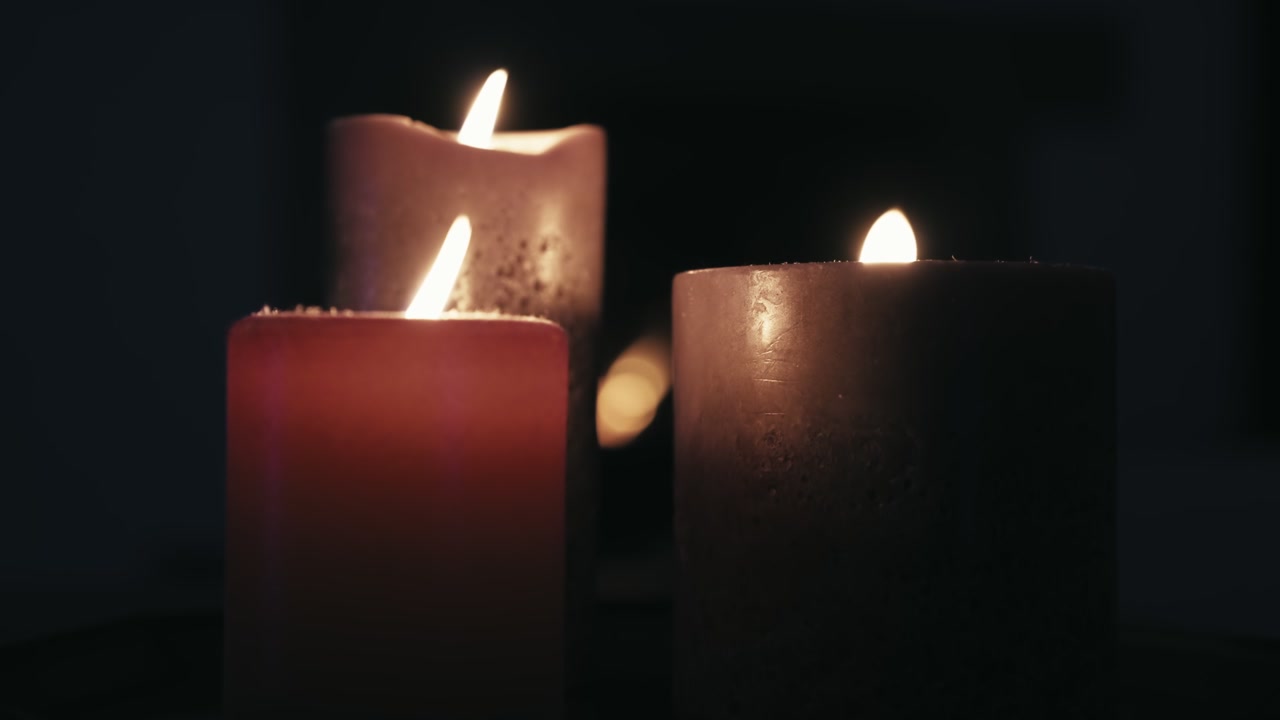 Scena romantica al rallentatore con candele accese davanti a un camino. Filmato scuro e calmo dall'atmosfera zen