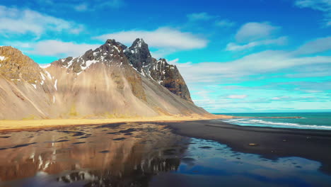 vestrahorn mountains with reflection on a sunny day in south iceland with blue sky on the background.  - panning shot