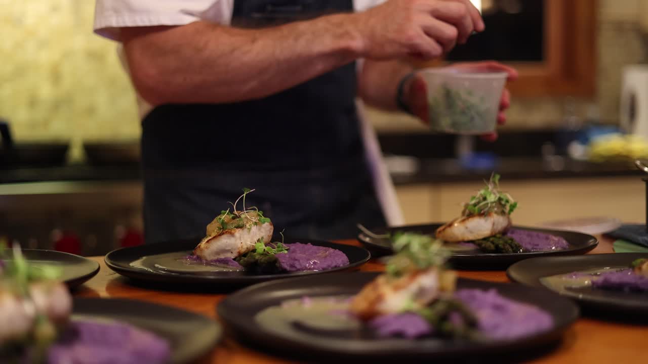 Chef che impiattano la portata principale con micro-ortaggi; Cucina gourmet