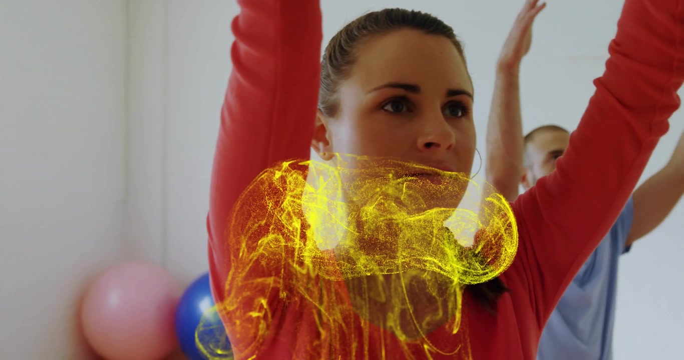 Donna che alza le braccia attivando una grafica gialla mentre un uomo la imita con palle da fitness.