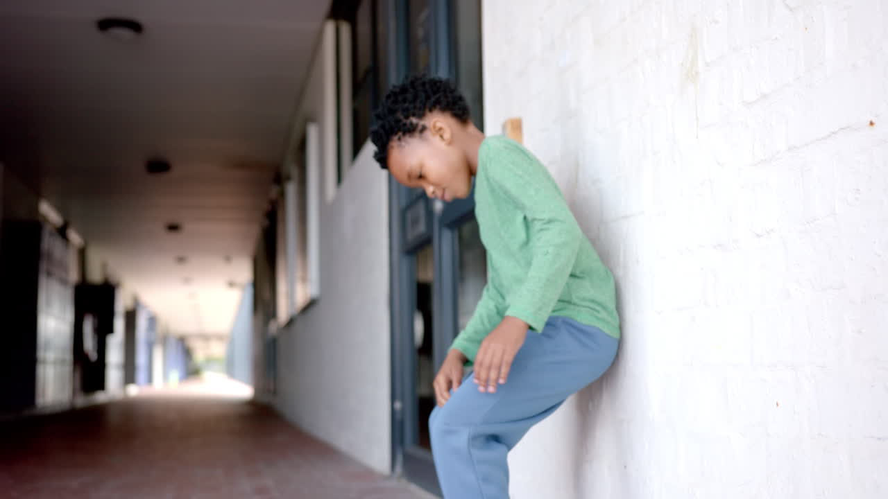 In school, upset boy sitting on the ground, feeling lonely or bullied