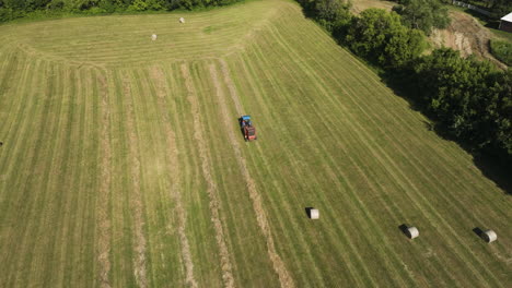 Bird's-eye-view-of-tractor-collecting-straw-hay-to-create-bale,-harvest-scene