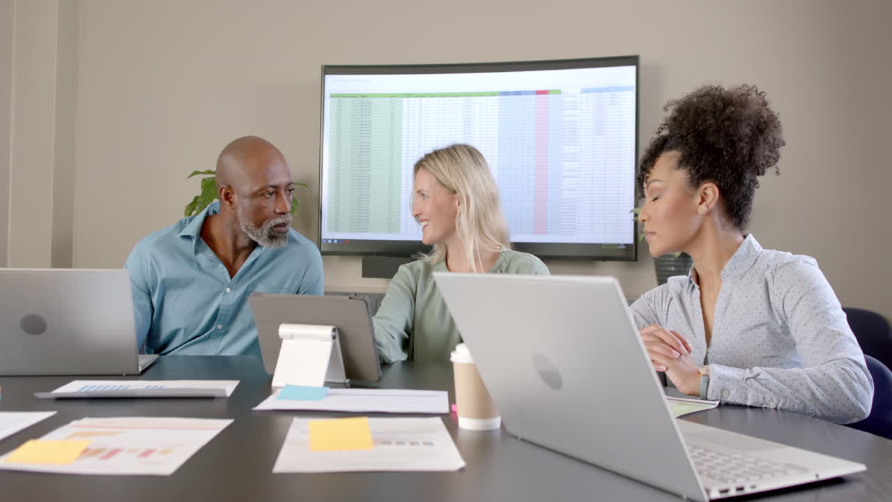 Diverse business people using laptops at conference table with copy space
