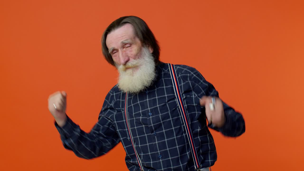 Äldre skäggig gråhårig morfar/farfar lyssnar på musik, ler, dansar till musik, har roligt.