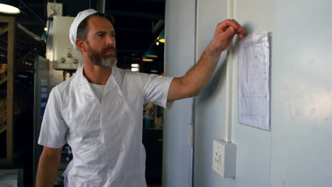 Chef-examining-sheet-hung-on-the-wall-4k