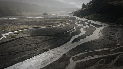 valle cinematográfico de thor, río glacial que fluye a través de un paisaje volcánico negro, puentes para cruzar ríos, thorsmörk, islandia