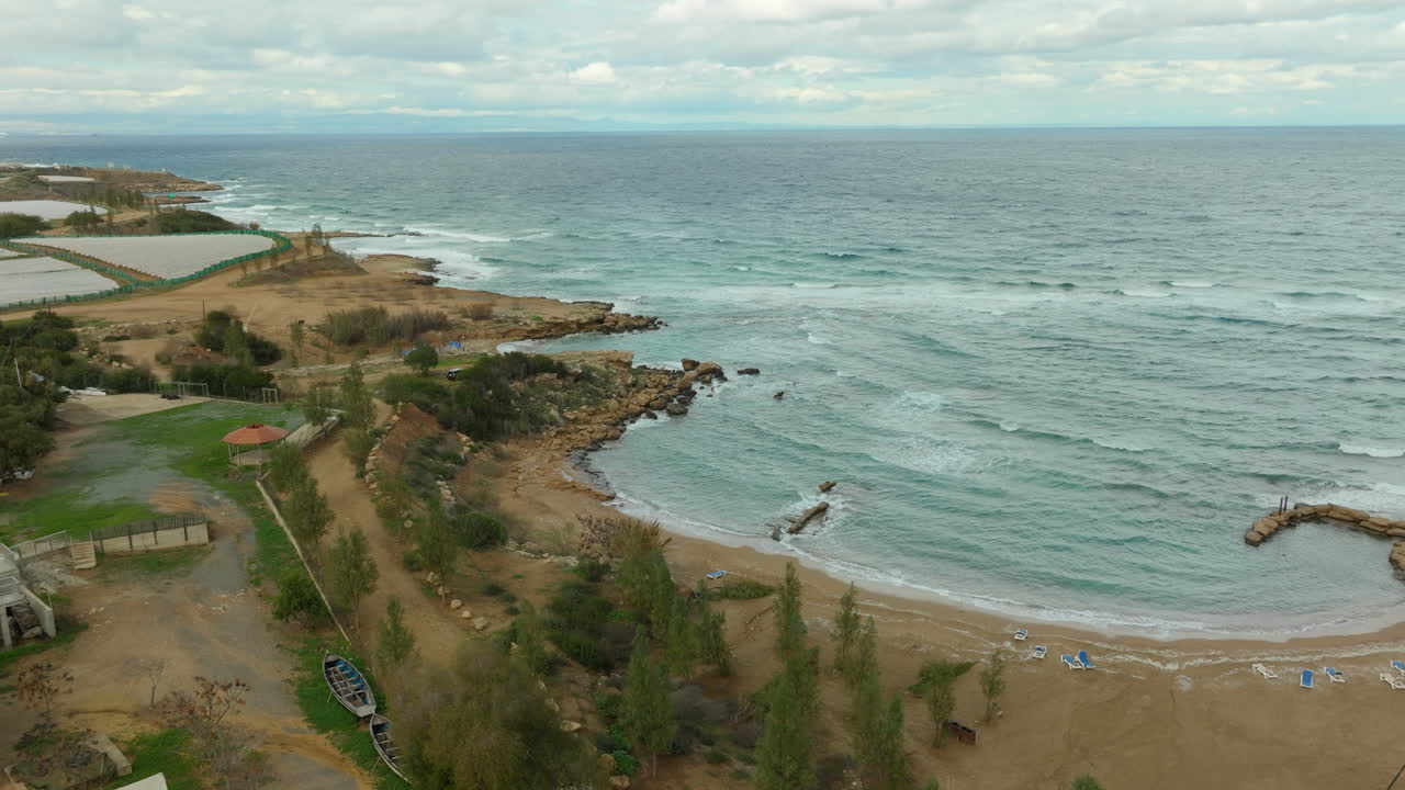vista costera de kapparis, paralimni, mostrando la playa, las costas rocosas y el mar mediterráneo contra un cielo nublado