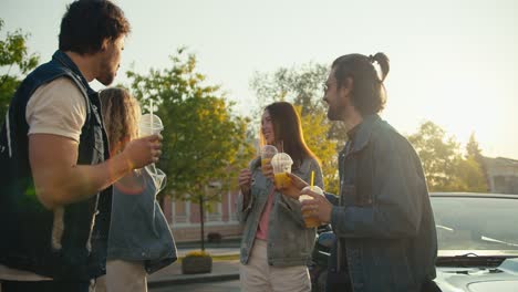 A-group-of-young-people-in-denim-jackets-stand-and-chat-on-the-street-near-their-own-car-on-a-sunny-evening