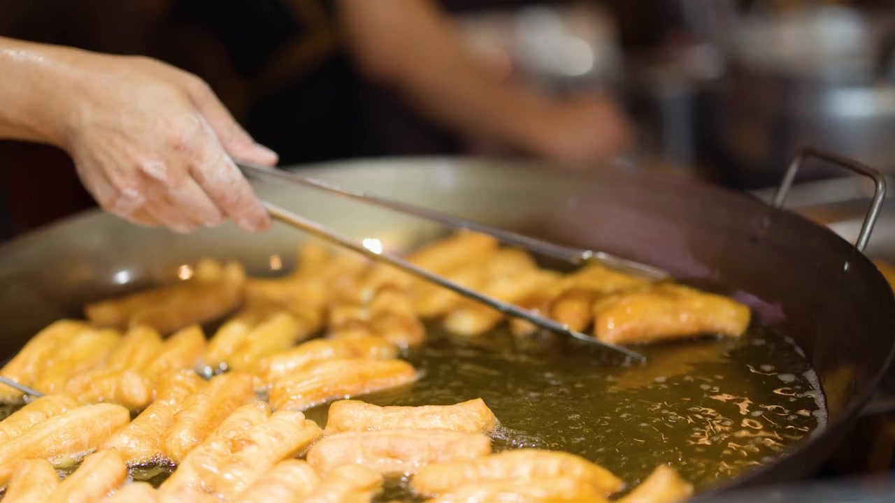 Chef che frigge ciambelle cinesi in un grande wok