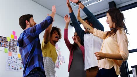 Smiling-graphic-designers-giving-high-five-during-meeting