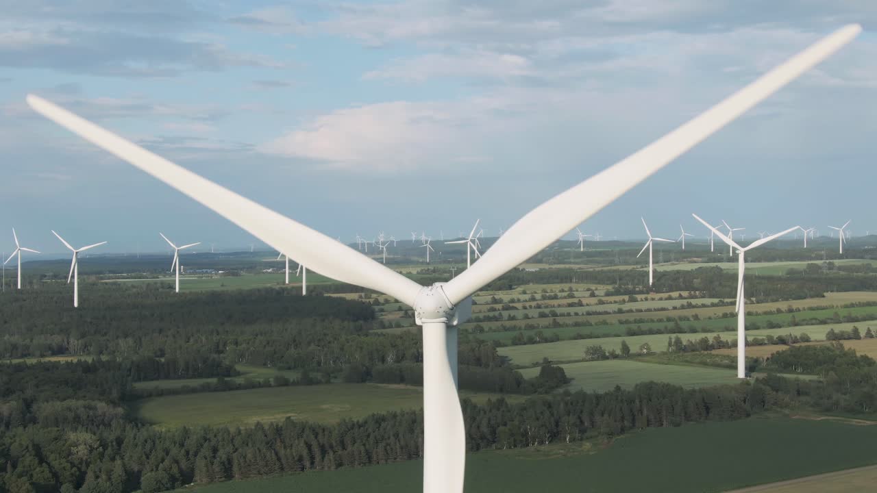 Close Up Details Of Wind Turbine Generating Renewable Energy On The Lush Field Near Saint Lawrence Gulf In Quebec, Canada - ascending drone shot