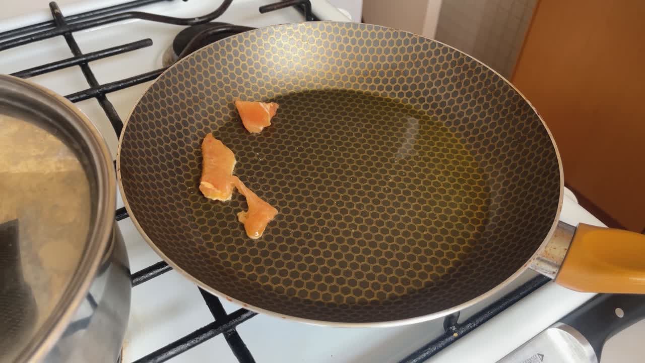 el cocinero agrega pedazos de pollo a la sartén con aceite caliente