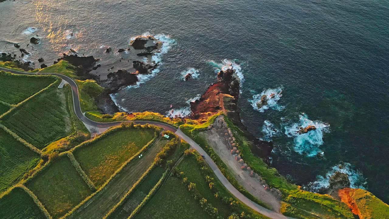 A rugged coastline with crashing waves and vibrant green fields, aerial view