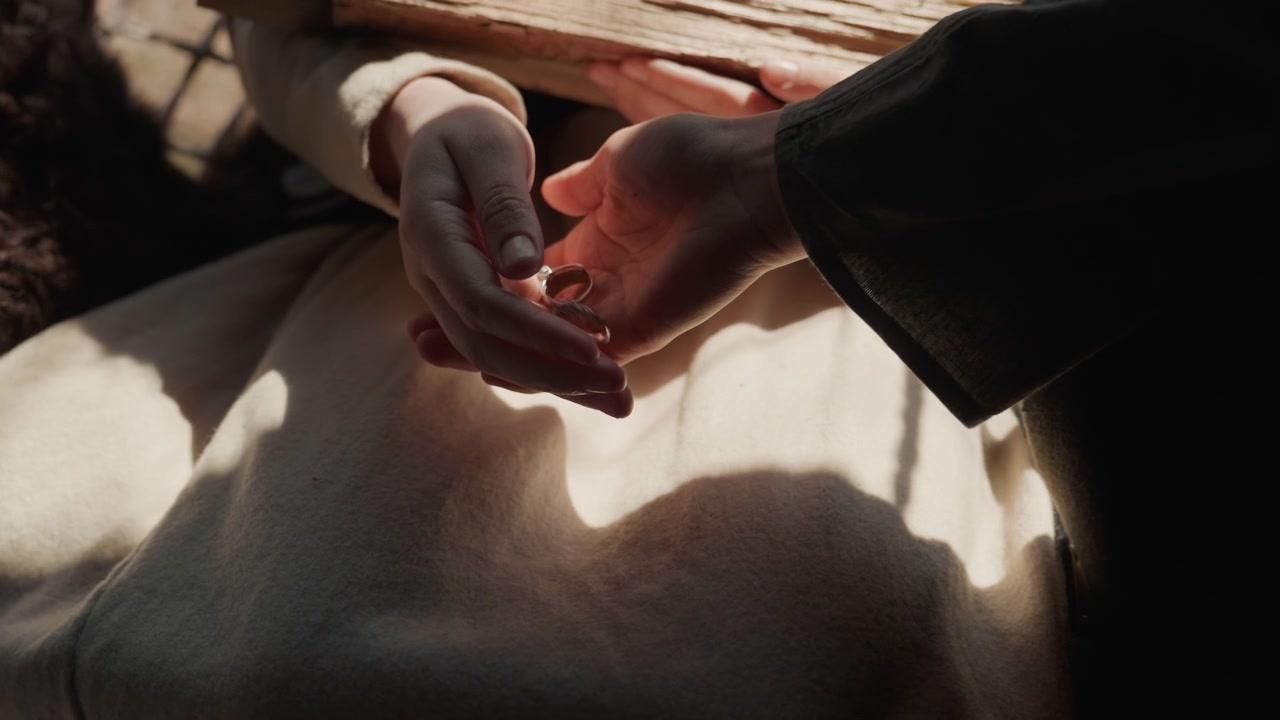 Primo piano che mostra una mano adulta che si protende verso il palmo aperto di un bambino piccolo sopra una coperta tessuta drappeggiata; i polpastrelli si toccano e le dita si chiudono leggermente, suggerendo comfort, protezione e una dolce famiglia.