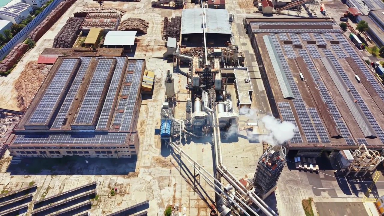 Sito industriale con pannelli solari e macchinari situato in un'area urbana durante una giornata di sole.