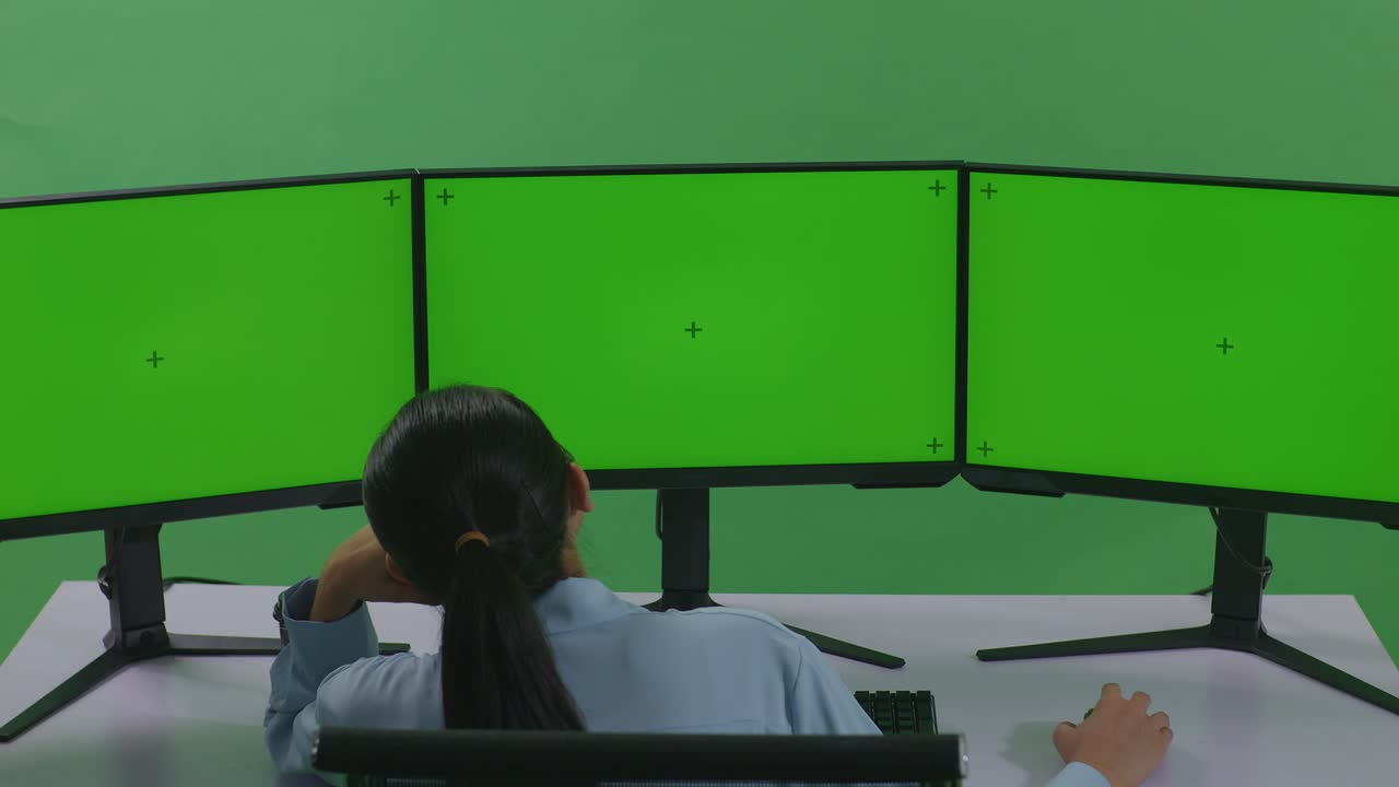 초록색 화면 을 가진 여러 컴퓨터 화면 앞 에 있는 사람