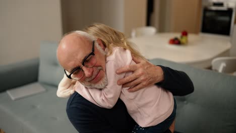 pequeña nieta abrazo viejo abuelo mayor en casa