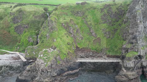 Un-Dron-Aéreo-Ascendente-Disparó-Sobre-Un-Hermoso-Paisaje-Con-Rocas-Y-Vistas-A-La-Hermosa-Naturaleza-Del-Camino-Del-Acantilado-De-Los-Gobbins-Del-Condado-De-Antrim-Durante-Una-Agradable-Mañana