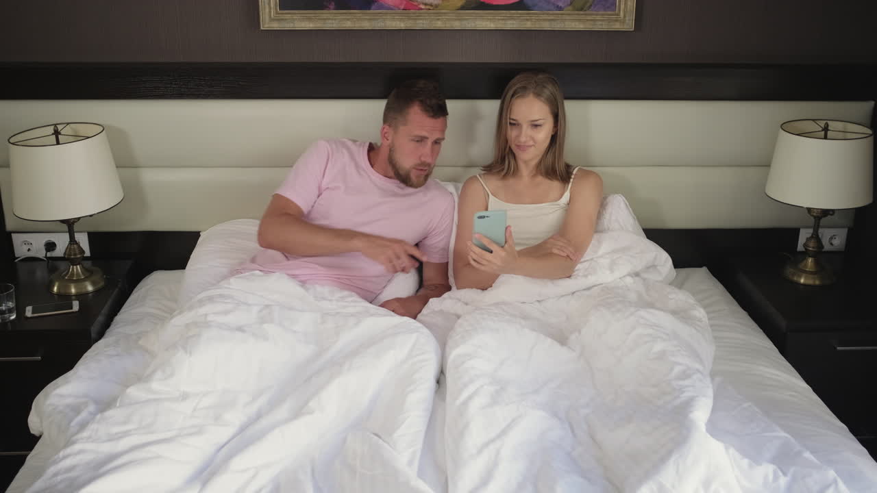 Couple Using Smartphone in Bed