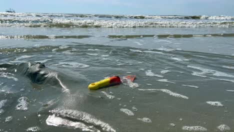 Juguete-De-Arena-En-La-Playa-Bañada-Por-Las-Olas