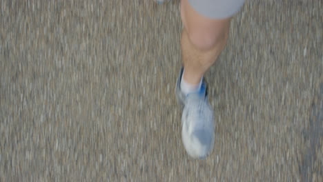 hombre caminando por el pavimento con zapatillas de deporte paseando con las piernas casuales en la vista superior de la ciudad