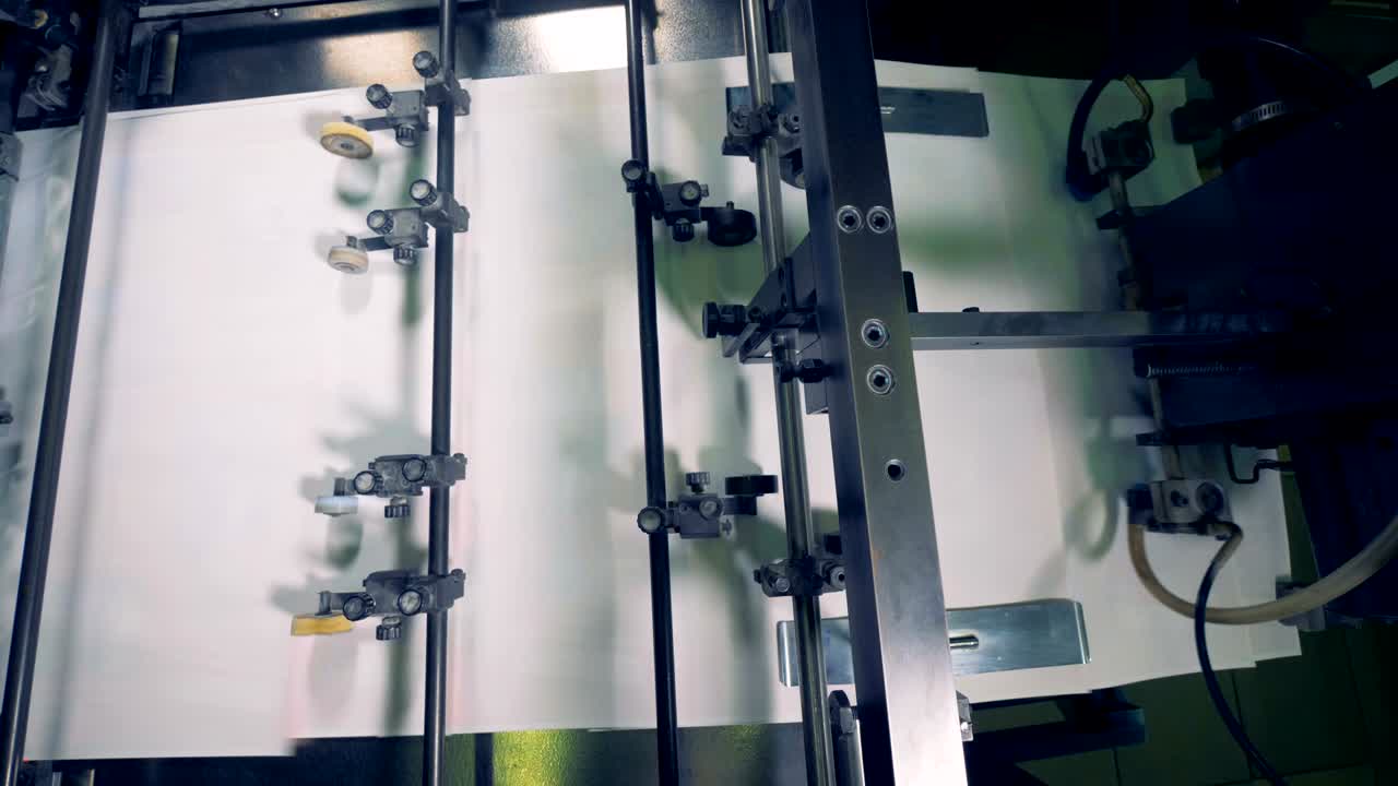 산업 기계는 종이 시트를 트레이로 어 모으고 움직이고 있습니다.