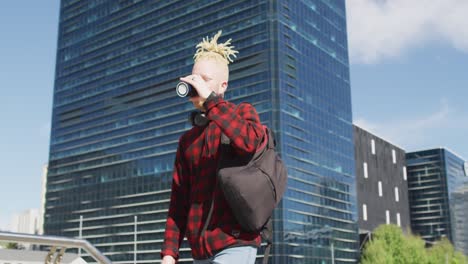 hombre albino afroamericano con rastas caminando y bebiendo café