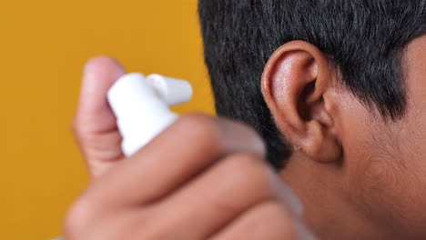 close up of men using spray to remove earwax