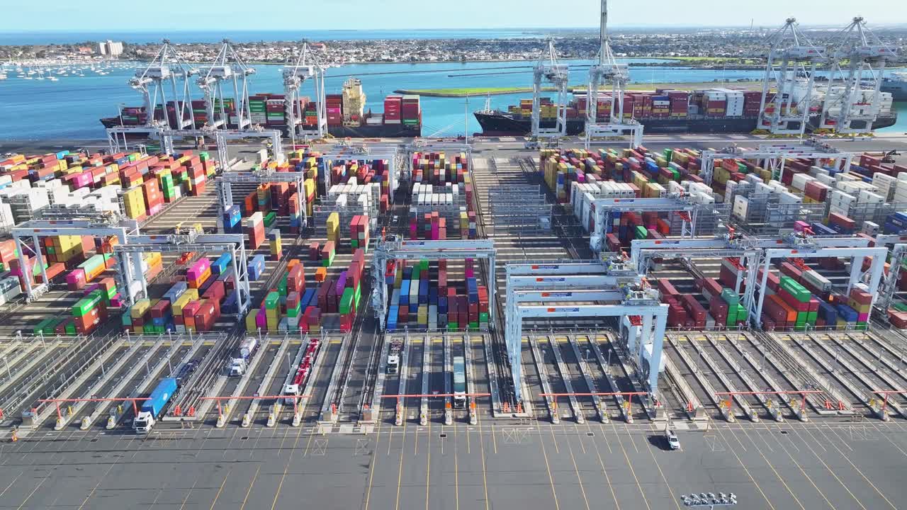 Rows of stacked freight containers and cranes at Melbourne port viewed from directly above