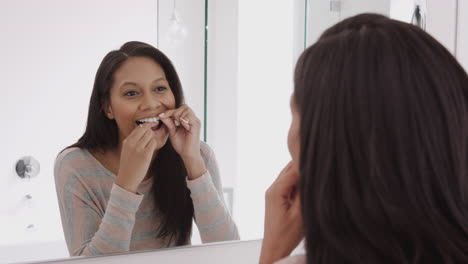 Spiegelbild-Einer-Frau,-Die-Zahnseide-Im-Badezimmerspiegel-Verwendet