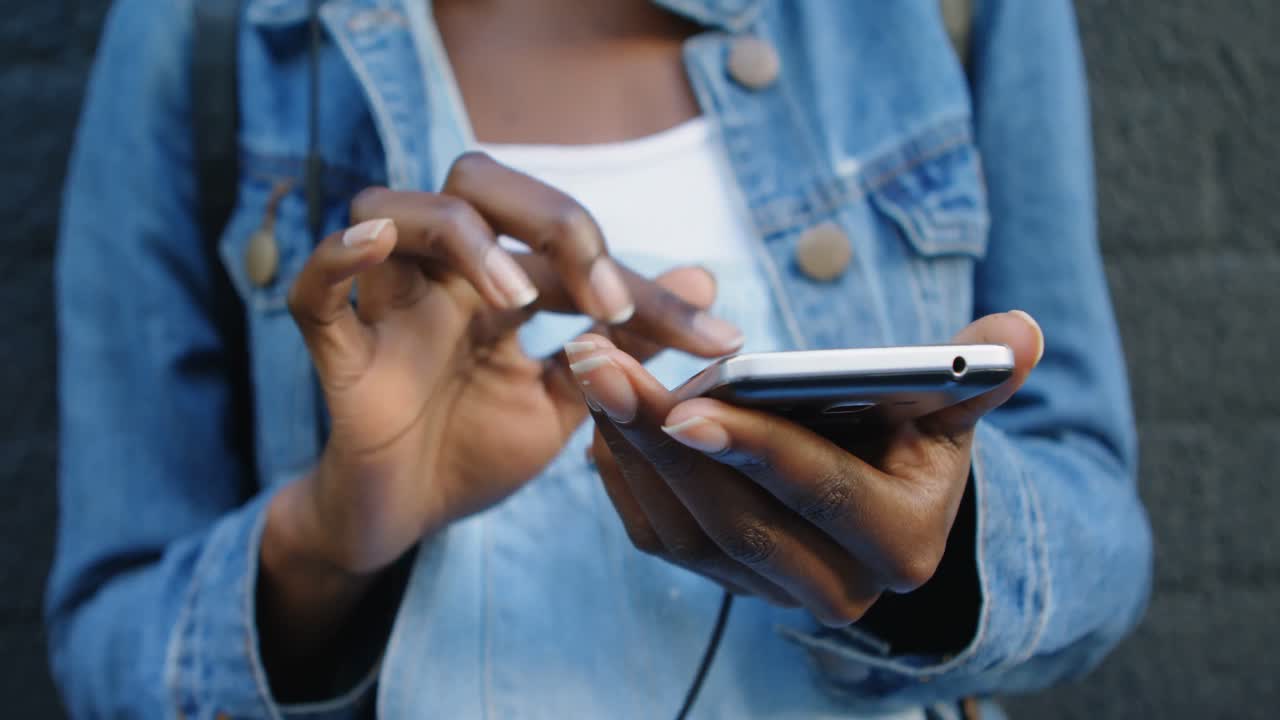 Woman using mobile phone while leaning against wall 4k