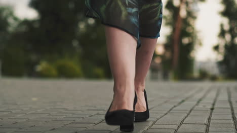 woman in stylish shoes and skirt walks along paved road