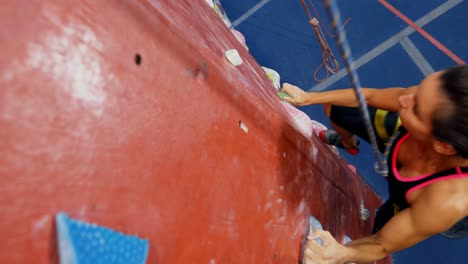 Woman-practicing-rock-climbing-in-fitness-studio-4k