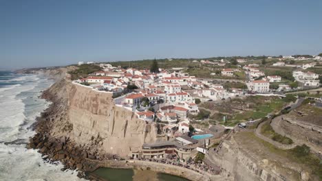 establecimiento de una toma panorámica con vistas a la ciudad parroquial en la cima del acantilado en azenhas do mar con olas rompiendo en la orilla