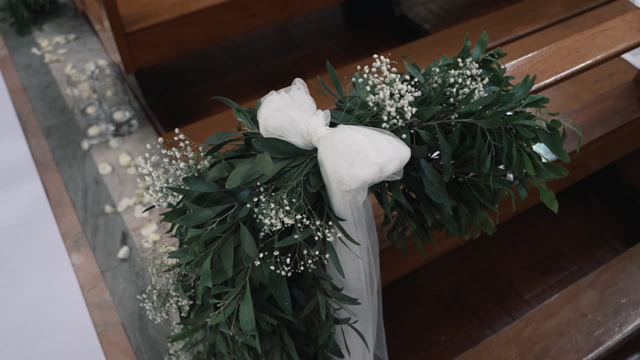 Elegante composizione floreale con nastro bianco e verde su una panchina di legno per un evento speciale.