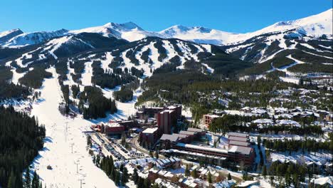 breckenridge, colorado aerial drone view of snowy ski slopes with chairlift and town with mountain homes and vacation rentals